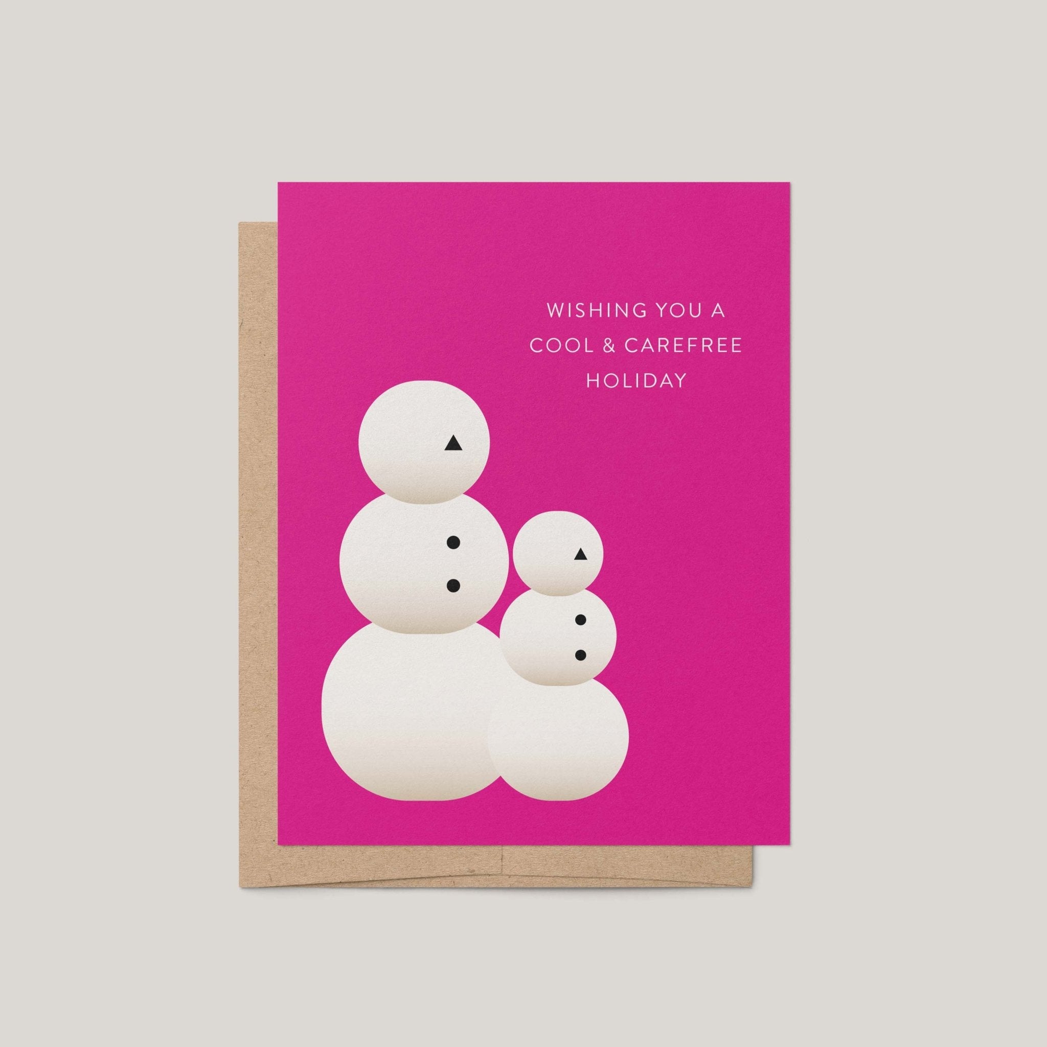Snow People holiday greeting card by Blú Rose, magenta card with minimalist snow people illustration and wishing you a cool and carefree holiday text, shown with kraft envelope
