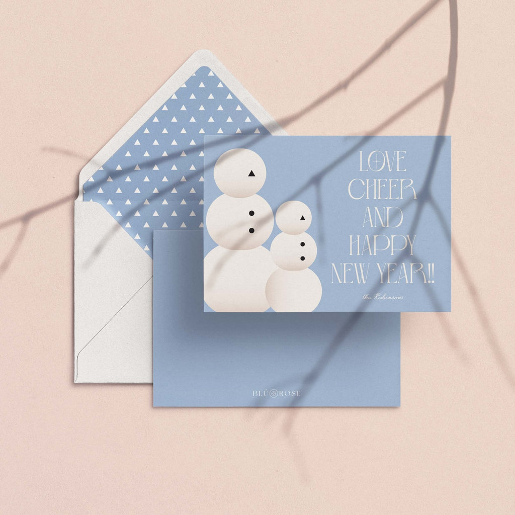 Snow People card with its blue dotted envelope liner styled on a blush backdrop