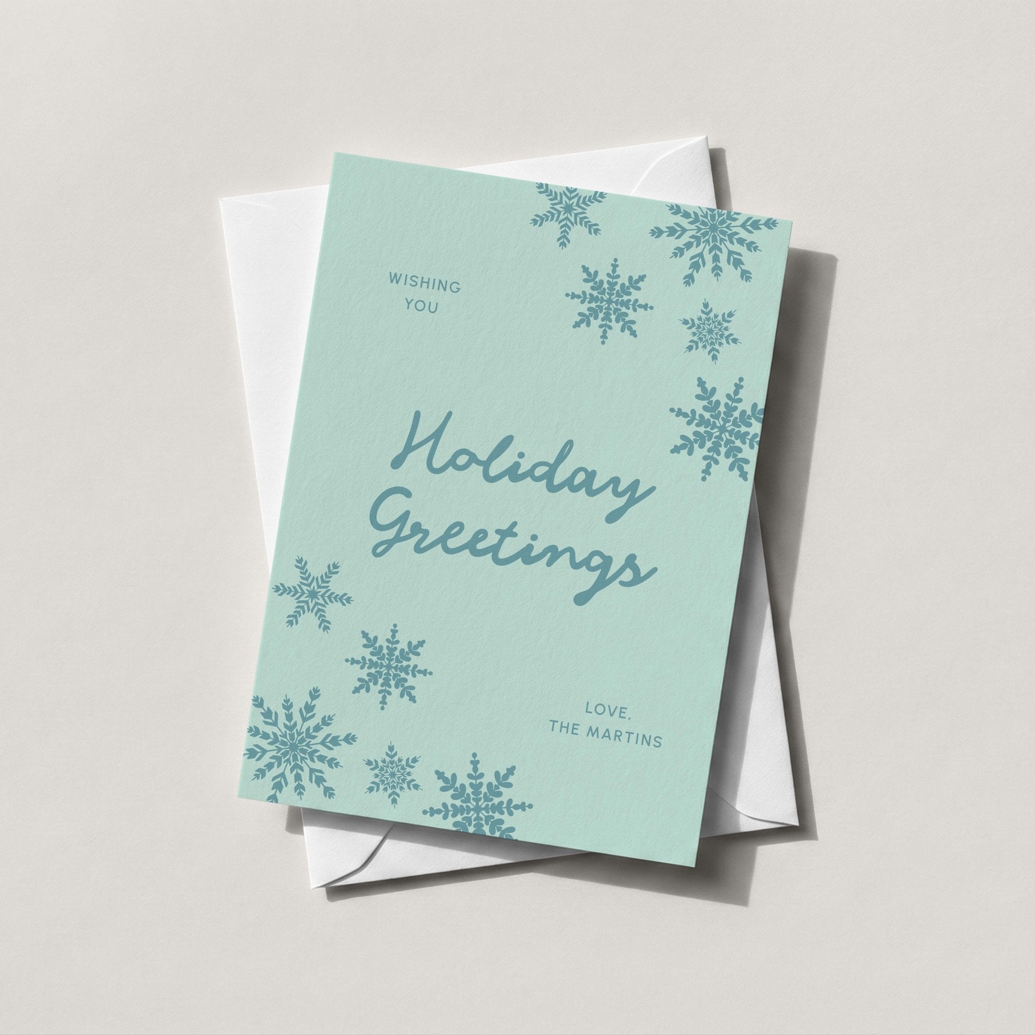 Snowflake Greetings card in soft teal with Holiday Greetings script and falling snowflakes