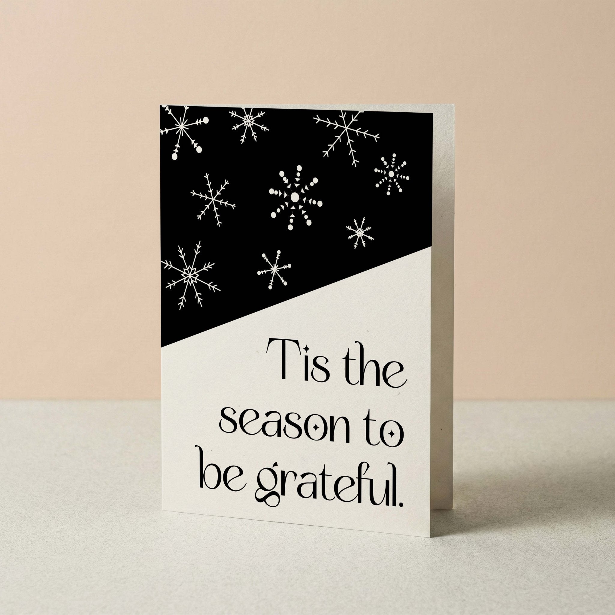 Snowflake Hill Christmas card by Blú Rose standing upright, black and cream snowflake design on a neutral background