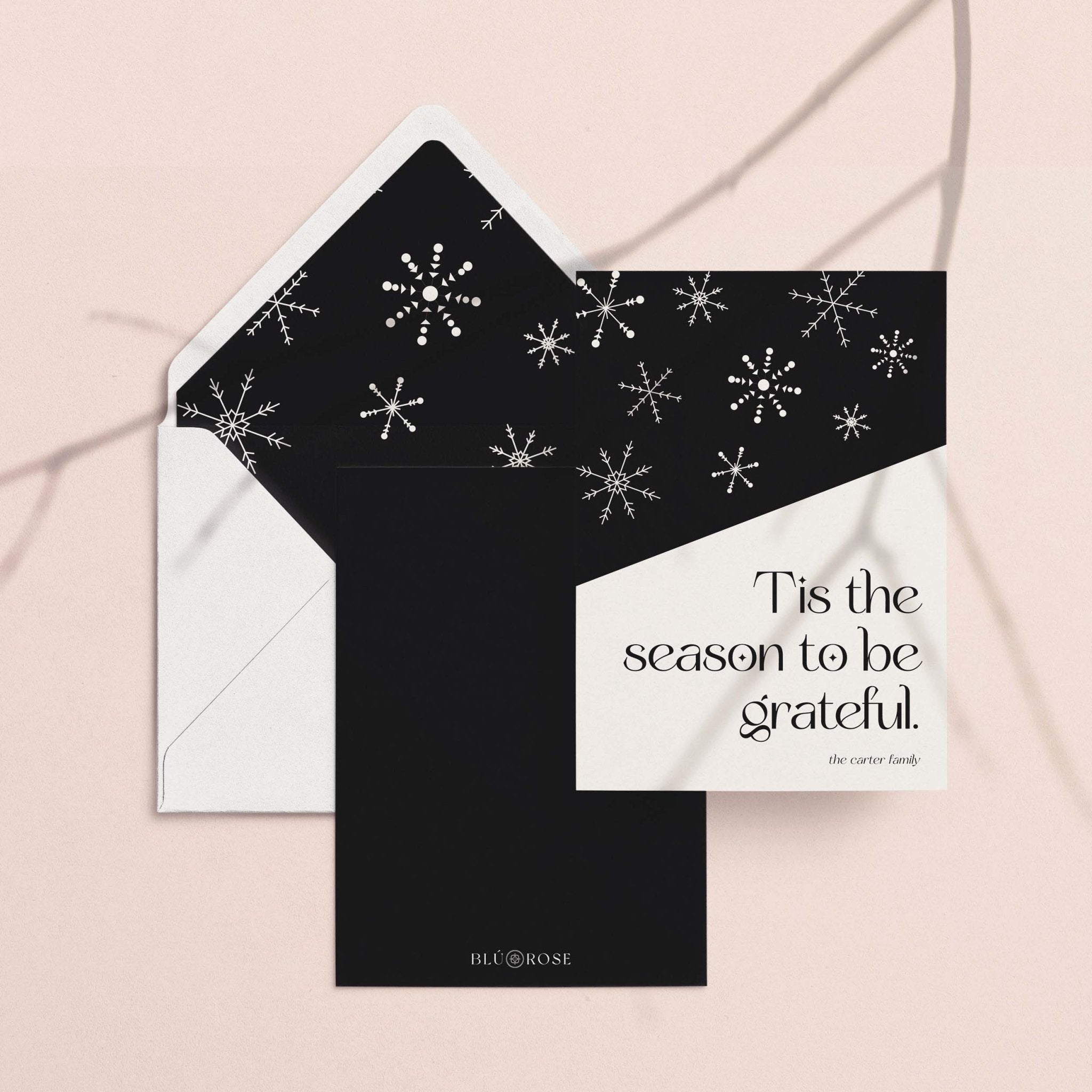 Snowflake Hill card with its black snowflake envelope liner styled on a blush backdrop
