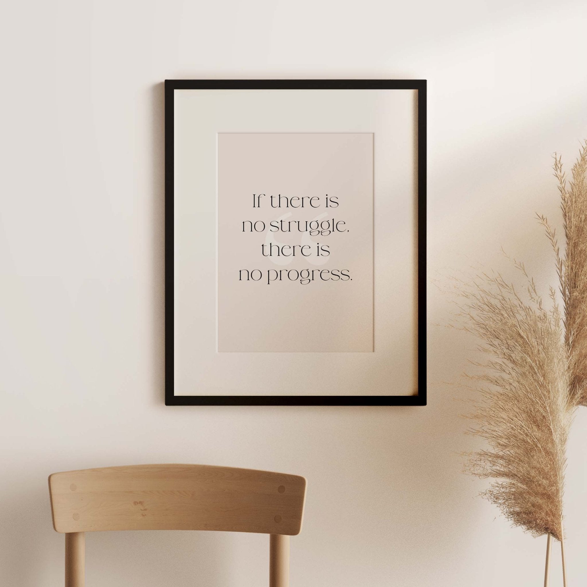 Black framed Frederick Douglass quote art print styled above wooden chair with pampas grass