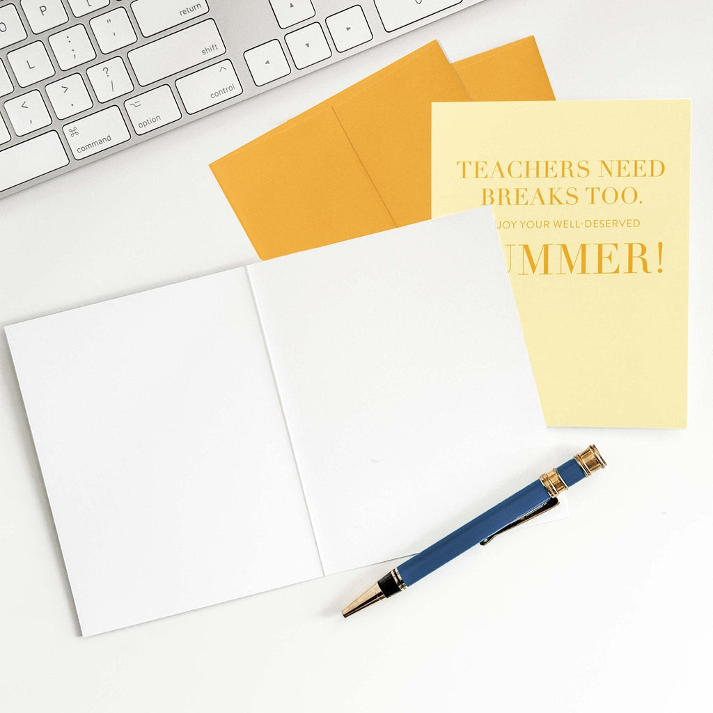 Teachers Need Breaks Too card by Blú Rose shown open with blank interior, marigold envelope and pen on a white desk