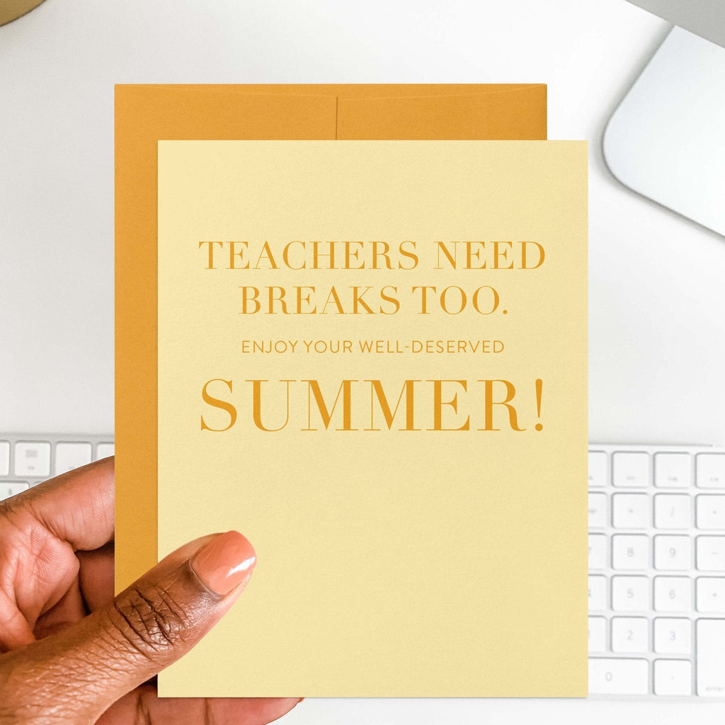 Teachers Need Breaks Too teacher card by Blú Rose held in hand over a white desk with keyboard and marigold envelope