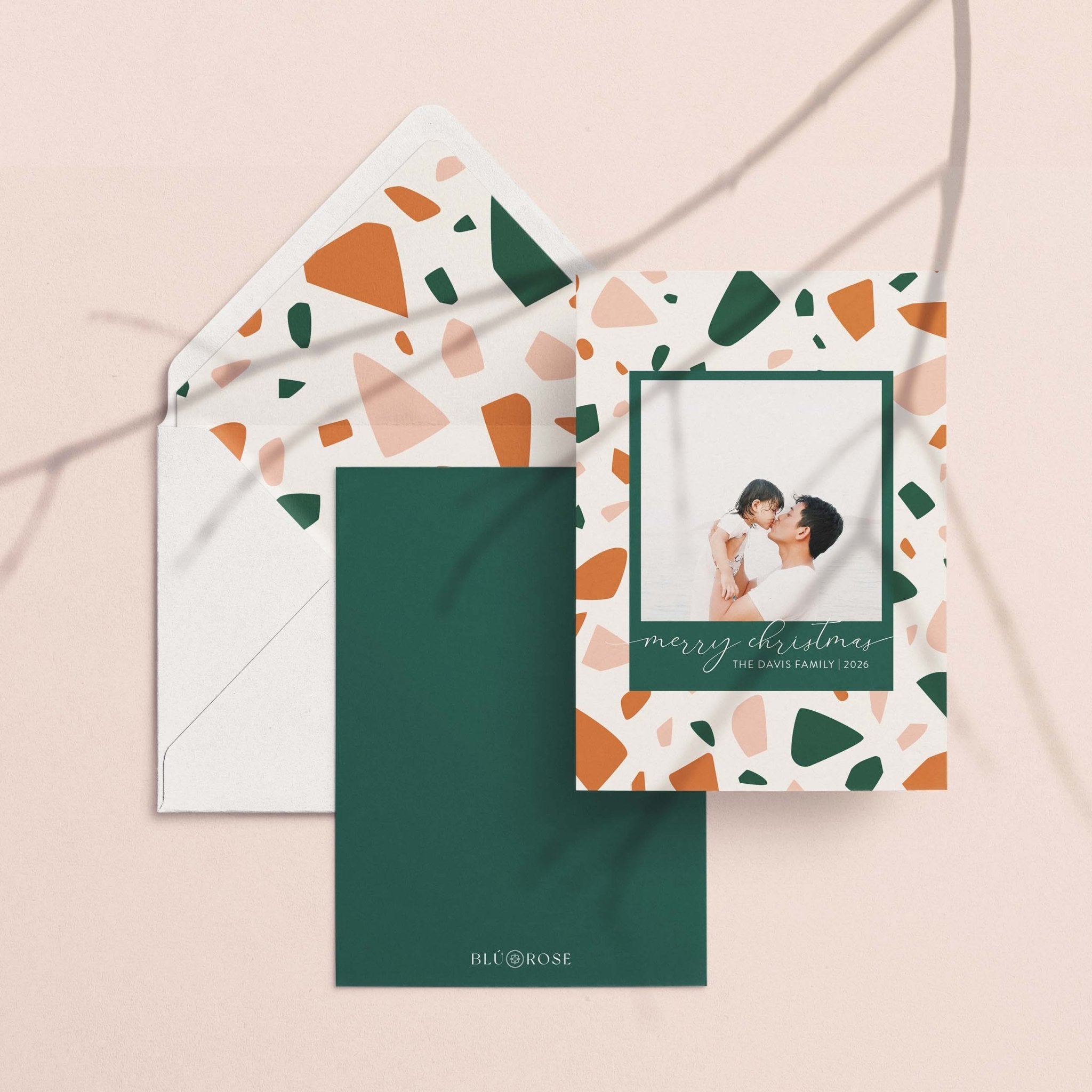 Terrazzo card with its terrazzo-print envelope liner and forest green backer on a neutral backdrop