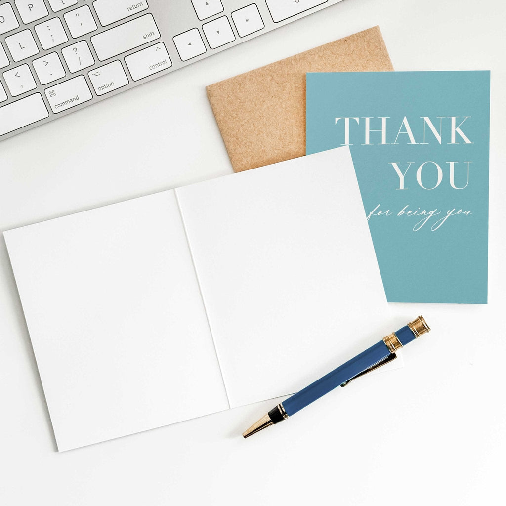 Thank You for Being You appreciation card by Blú Rose held in hand over a white desk with keyboard and kraft envelope