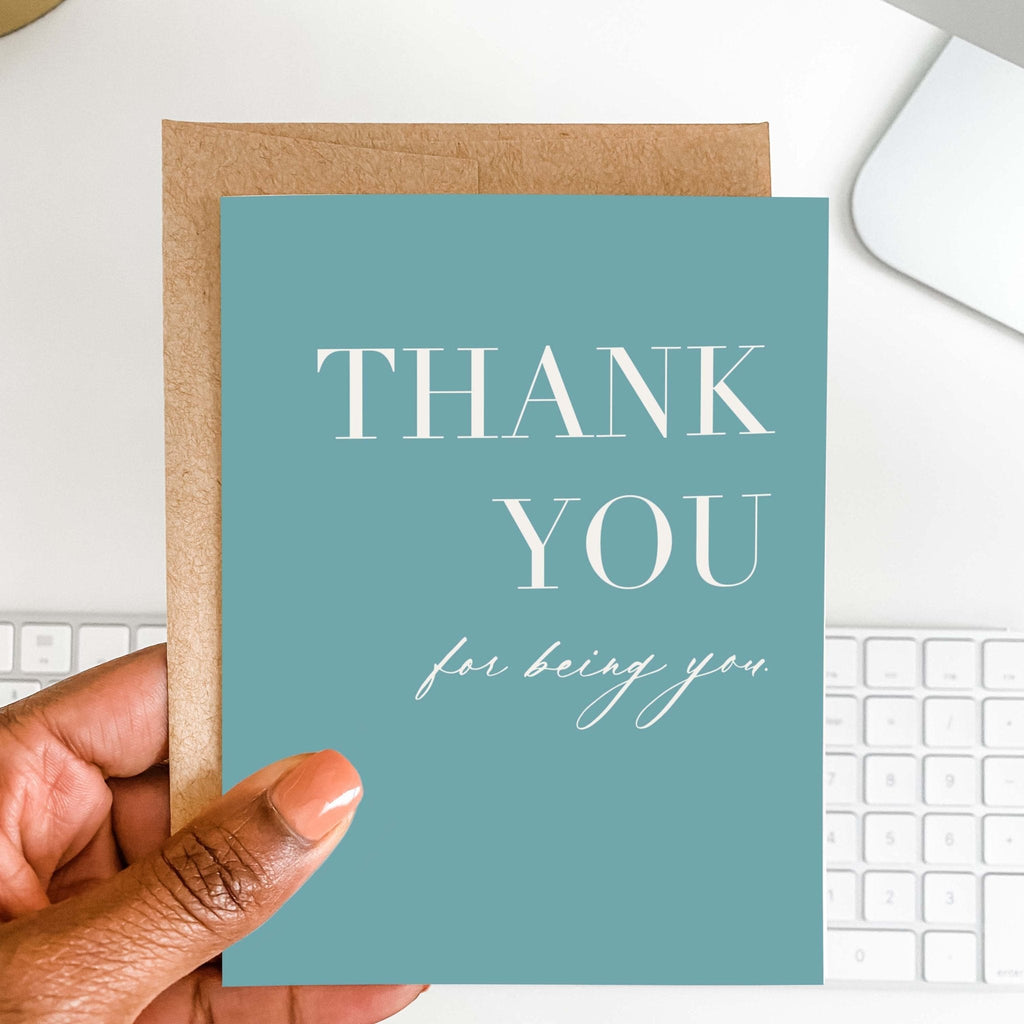 Thank You for Being You card by Blú Rose shown open with blank interior, kraft envelope and pen on a white desk