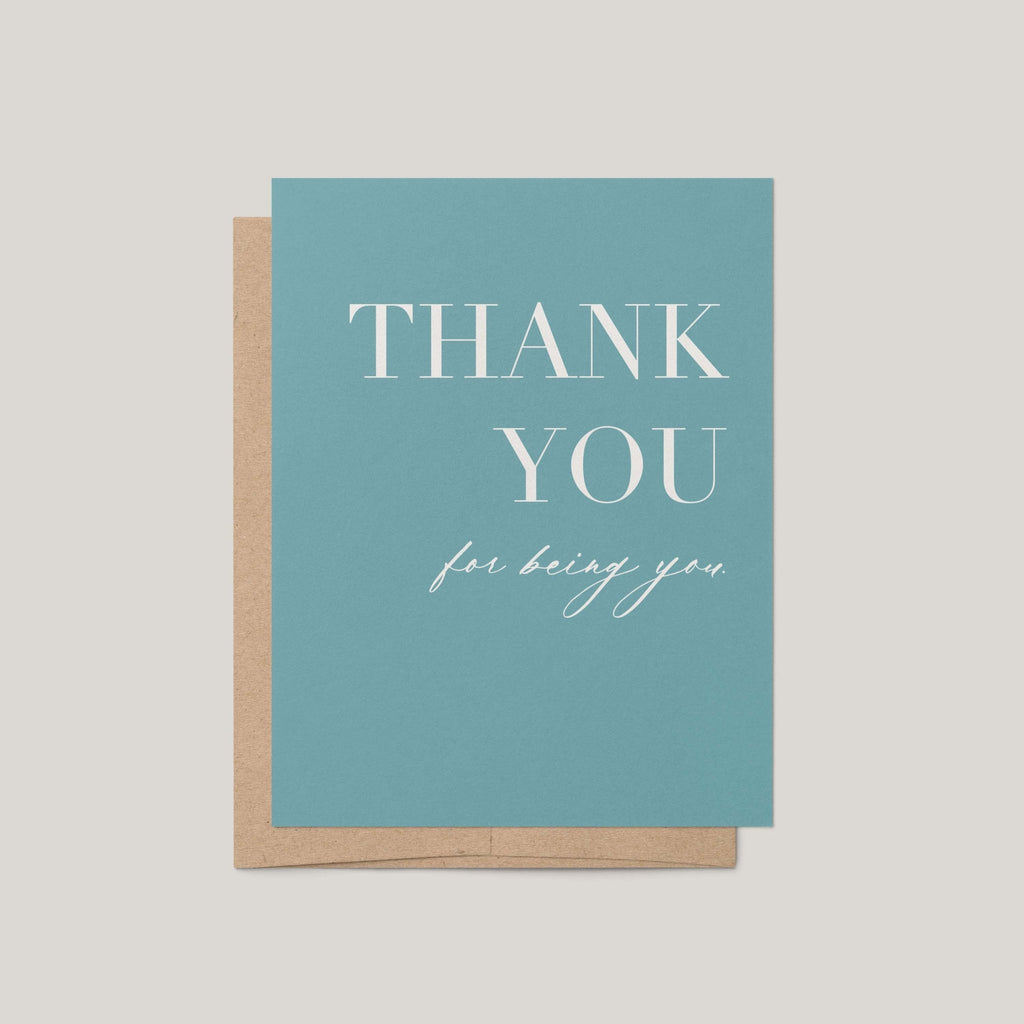 A teal thank you card with white text reading 'THANK YOU for being you,' shown with a kraft paper envelope on a light beige background.