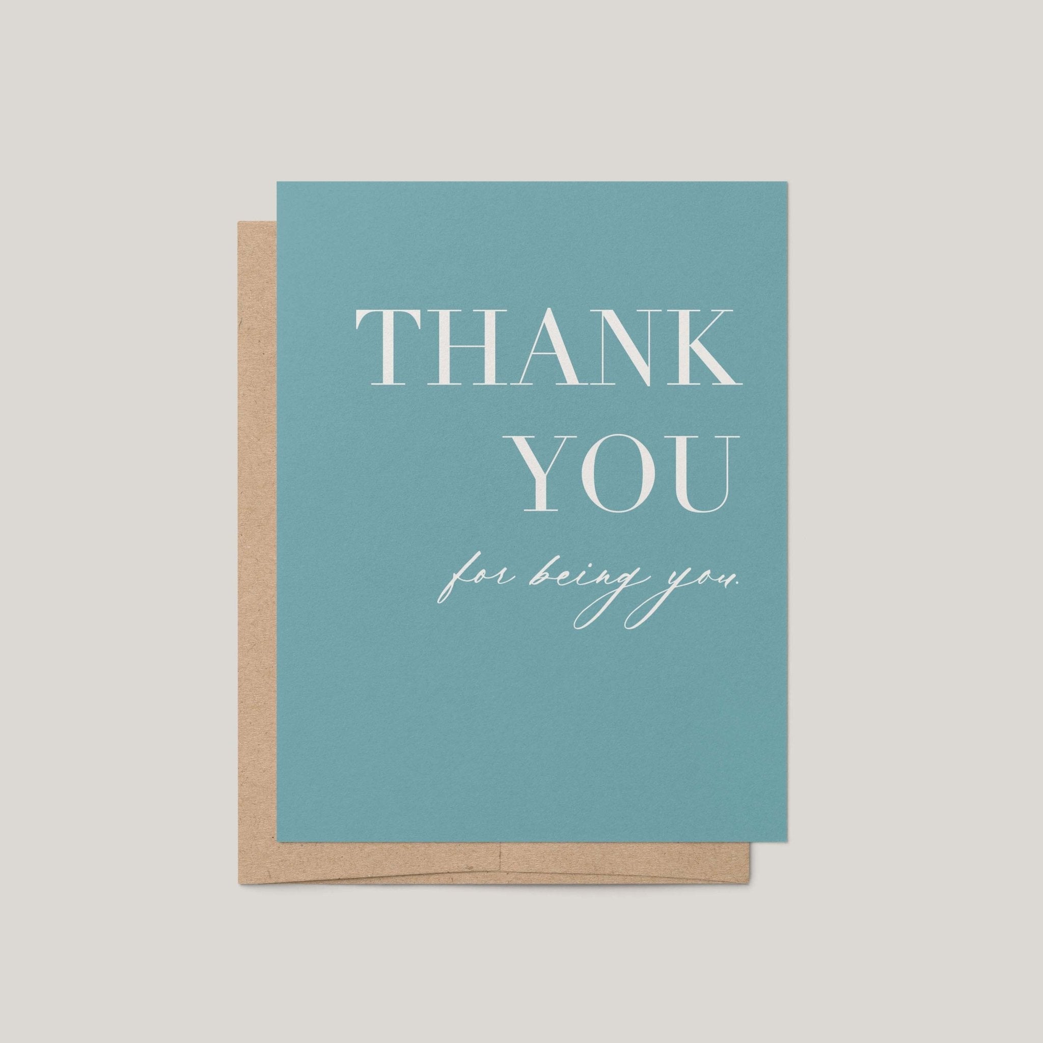 A teal thank you card with white text reading 'THANK YOU for being you,' shown with a kraft paper envelope on a light beige background.