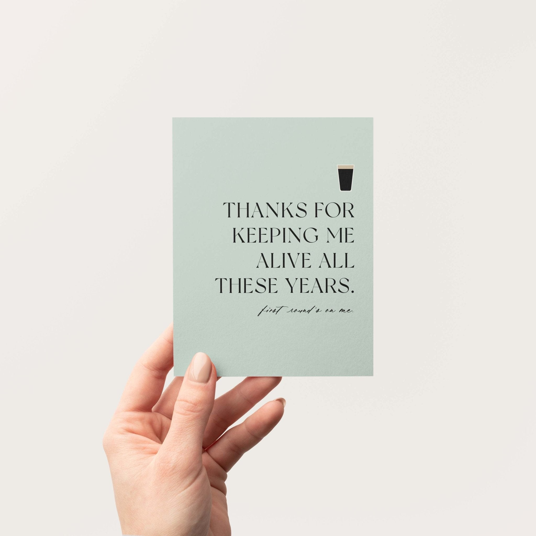 Thanks for Keeping Me Alive greeting card by Blú Rose held in hand against a neutral off-white background