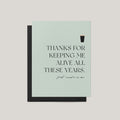 Thanks for Keeping Me Alive funny Father's Day greeting card by Blú Rose, sage card with beer pint illustration and first round's on me text, shown with black envelope