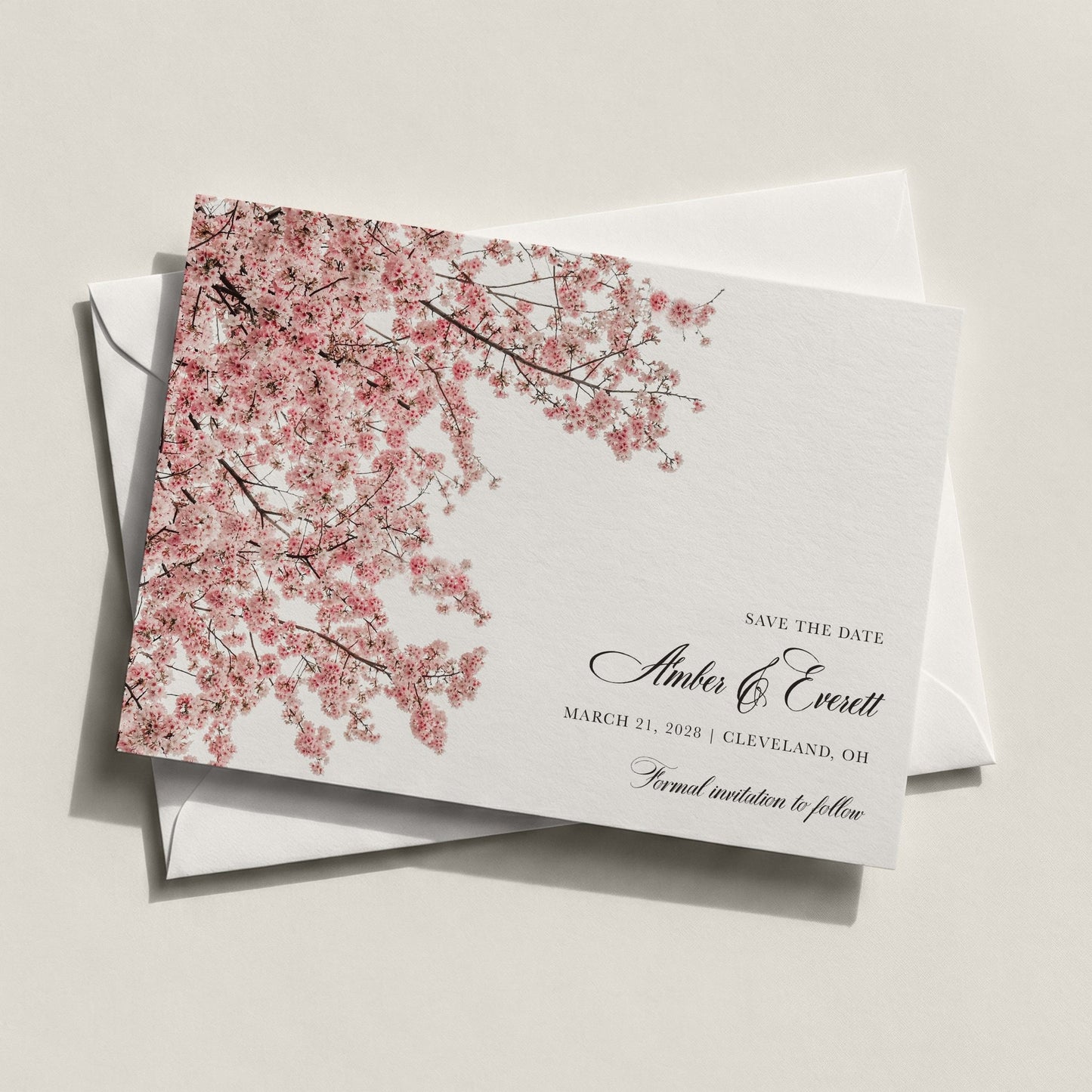The Cherry Blossom Save the Date by Blú Rose featuring cascading pink cherry blossom branches with classic black script on white cardstock displayed on a white envelope