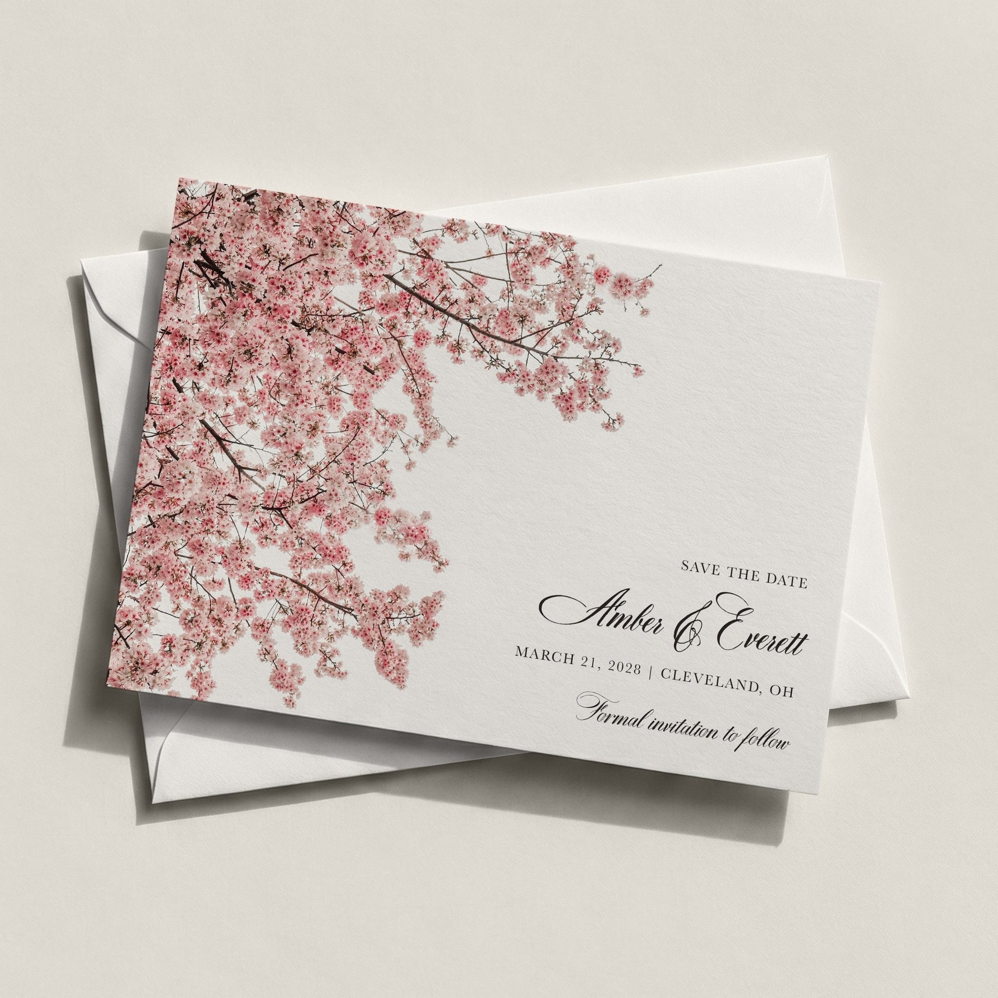 The Cherry Blossom Save the Date by Blú Rose featuring cascading pink cherry blossom branches with classic black script on white cardstock displayed on a white envelope