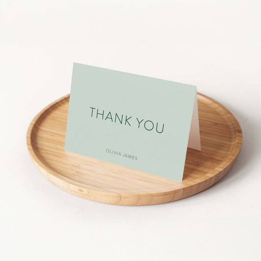 The Olivia personalized thank you card by Blú Rose in sage green displayed folded on a round bamboo tray