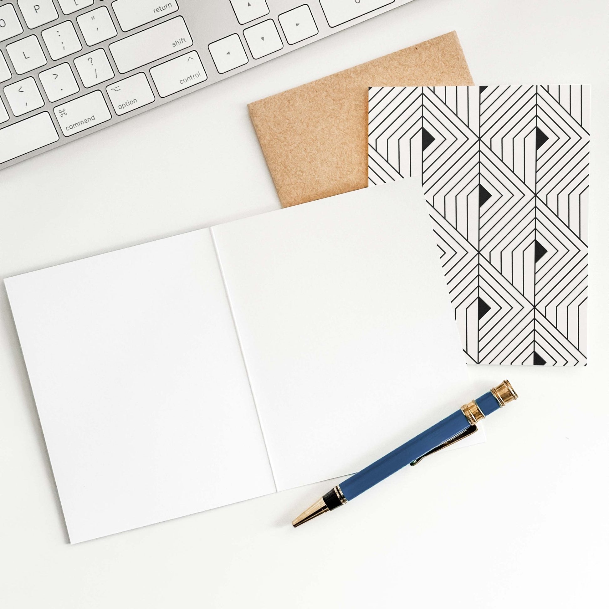 The Prism Greeting Card by Blú Rose shown open to reveal blank inside with pen on a white desk alongside kraft envelope