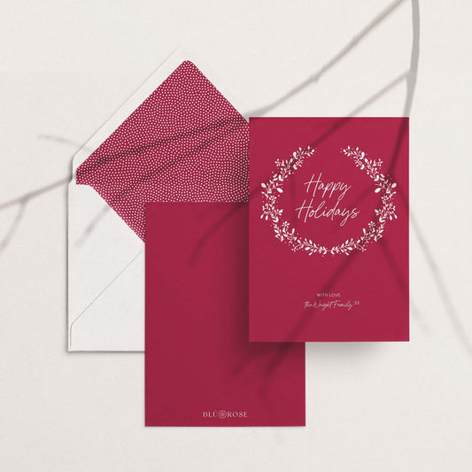 Personalized holiday card with matching red patterned envelope liner, flat lay on white background.
