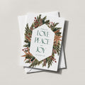 Winter Wreath holiday card with a pine and berry wreath framing LOVE PEACE CHEER, on a white envelope