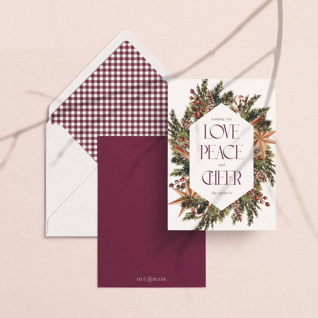 Winter Wreath card with its burgundy gingham envelope liner styled on a blush backdrop