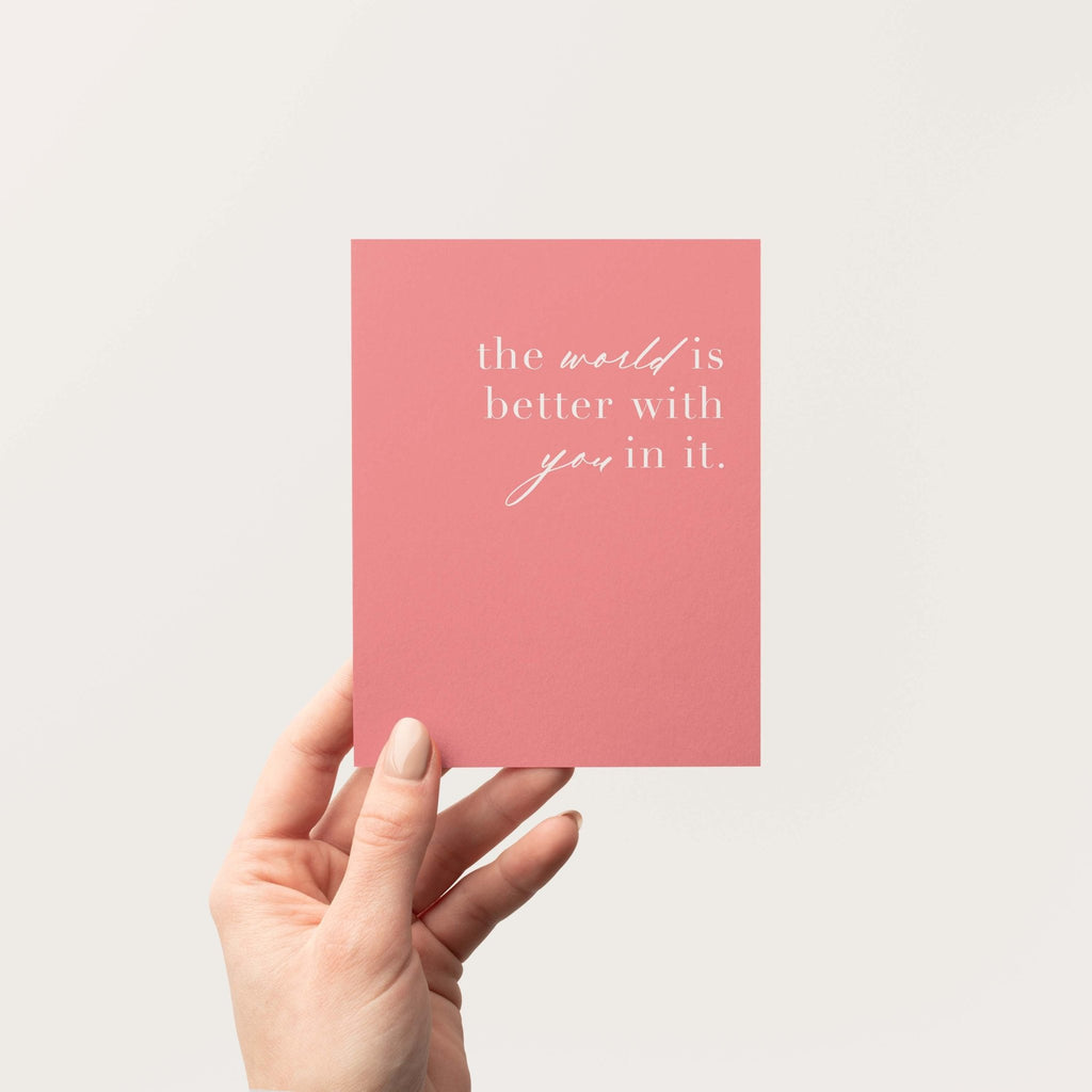 World is Better With You greeting card by Blú Rose held in hand against a neutral off-white background