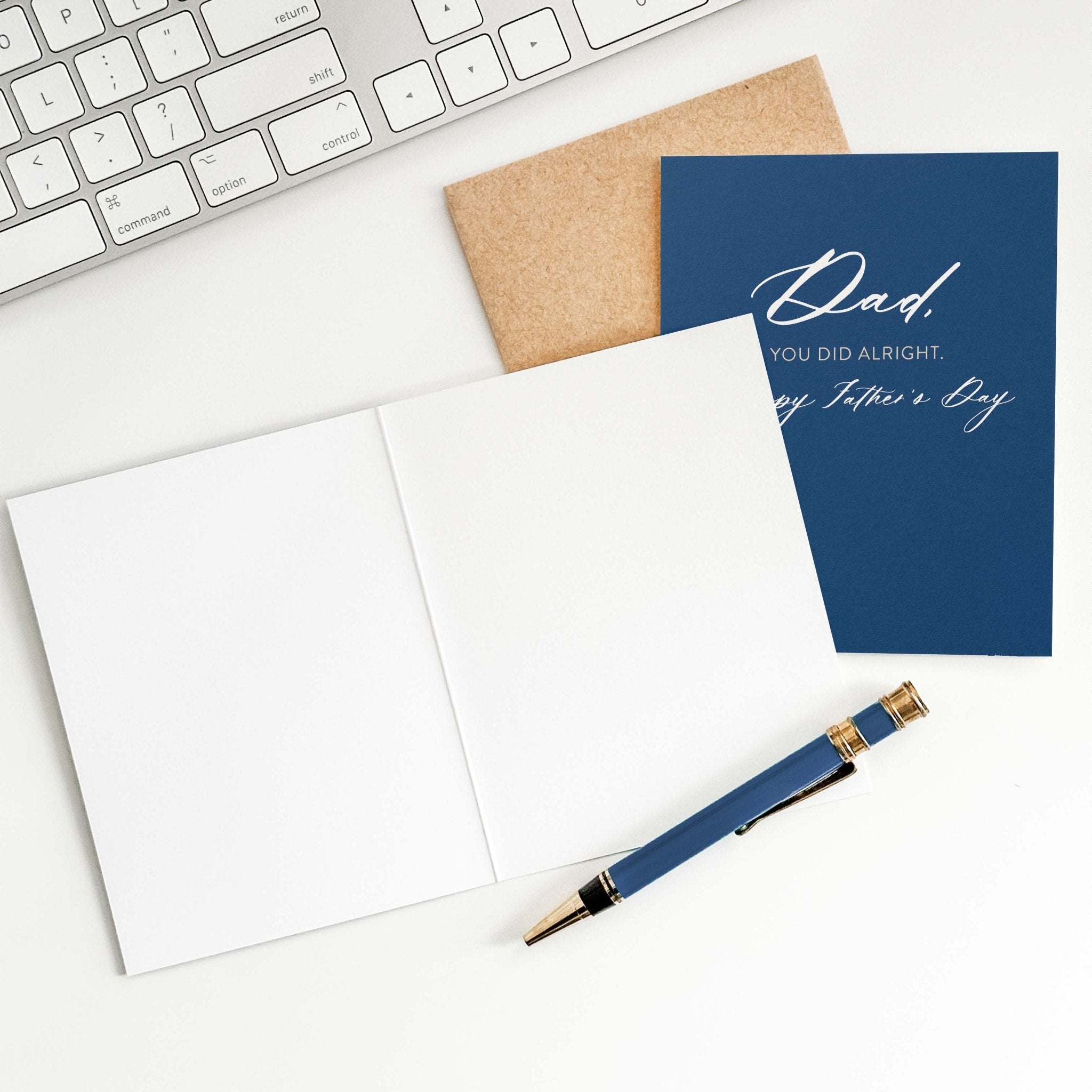 You Did Alright card by Blú Rose shown open with blank interior, kraft envelope and pen on a white desk