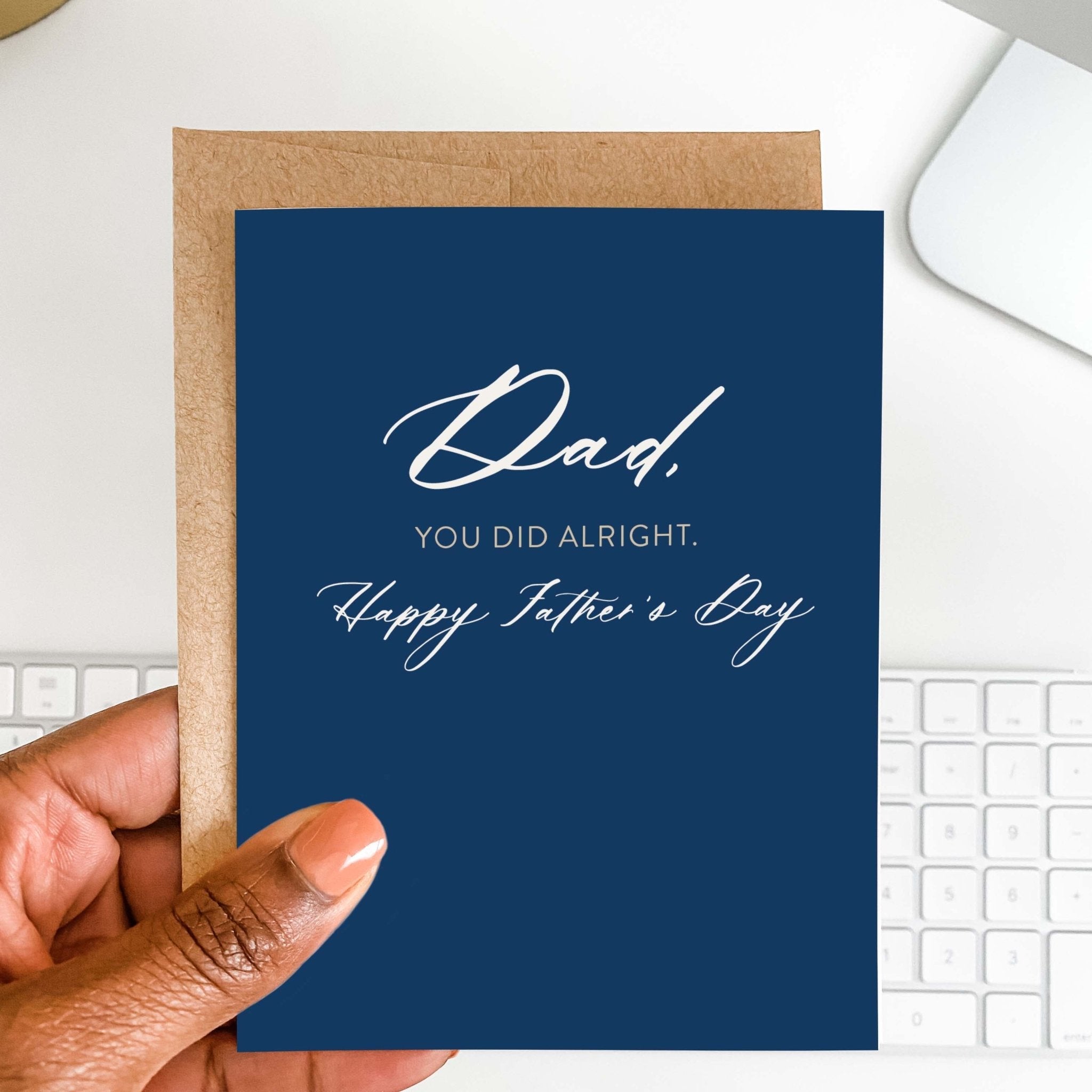 You Did Alright Father's Day card by Blú Rose held in hand over a white desk with keyboard and kraft envelope