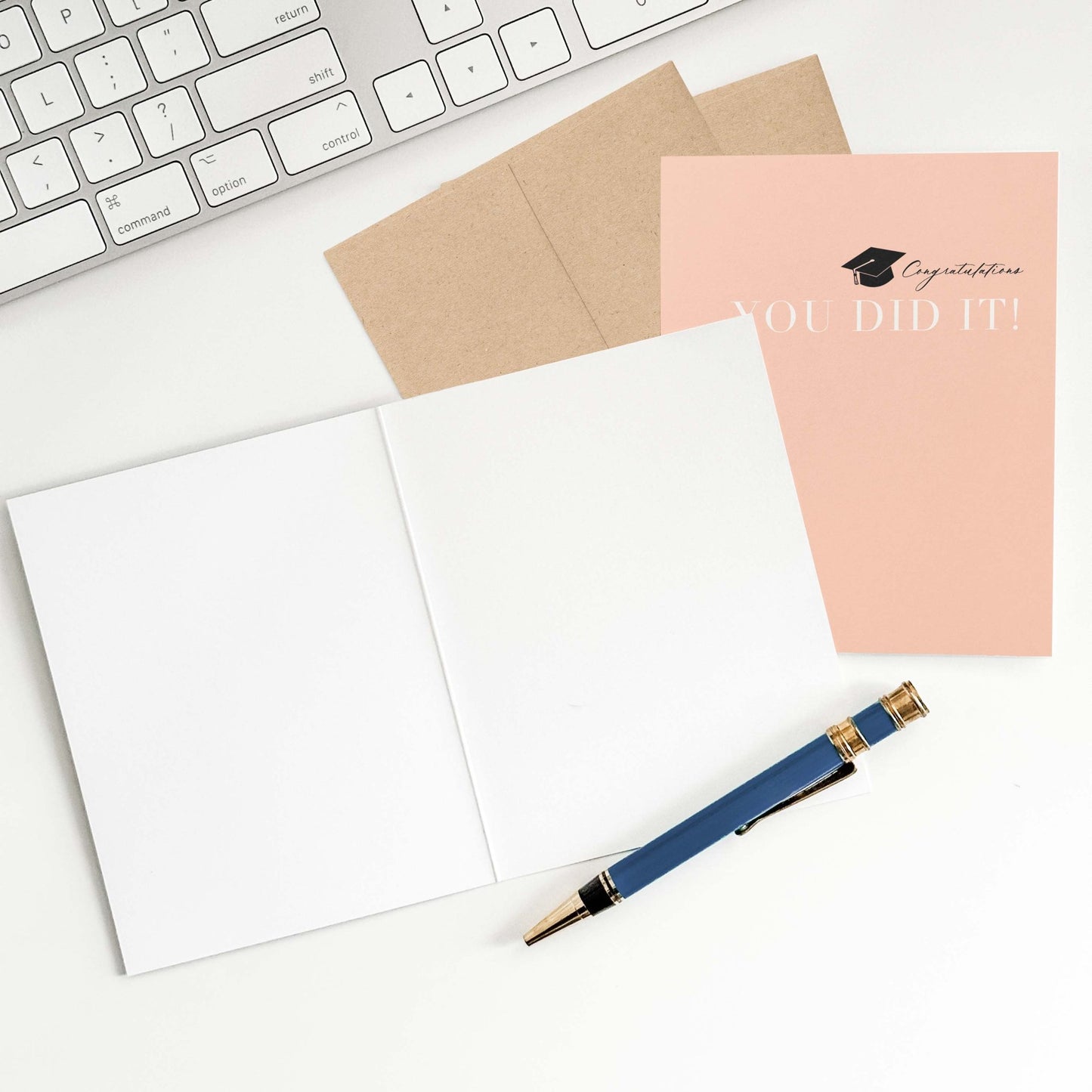 Peach graduation card with open blank interior, envelope, and pen