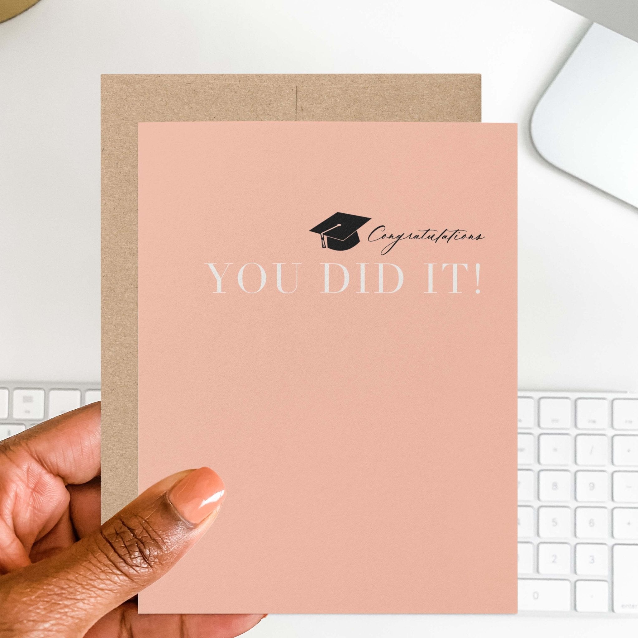 Hand holding peach graduation congratulations card that reads You Did It
