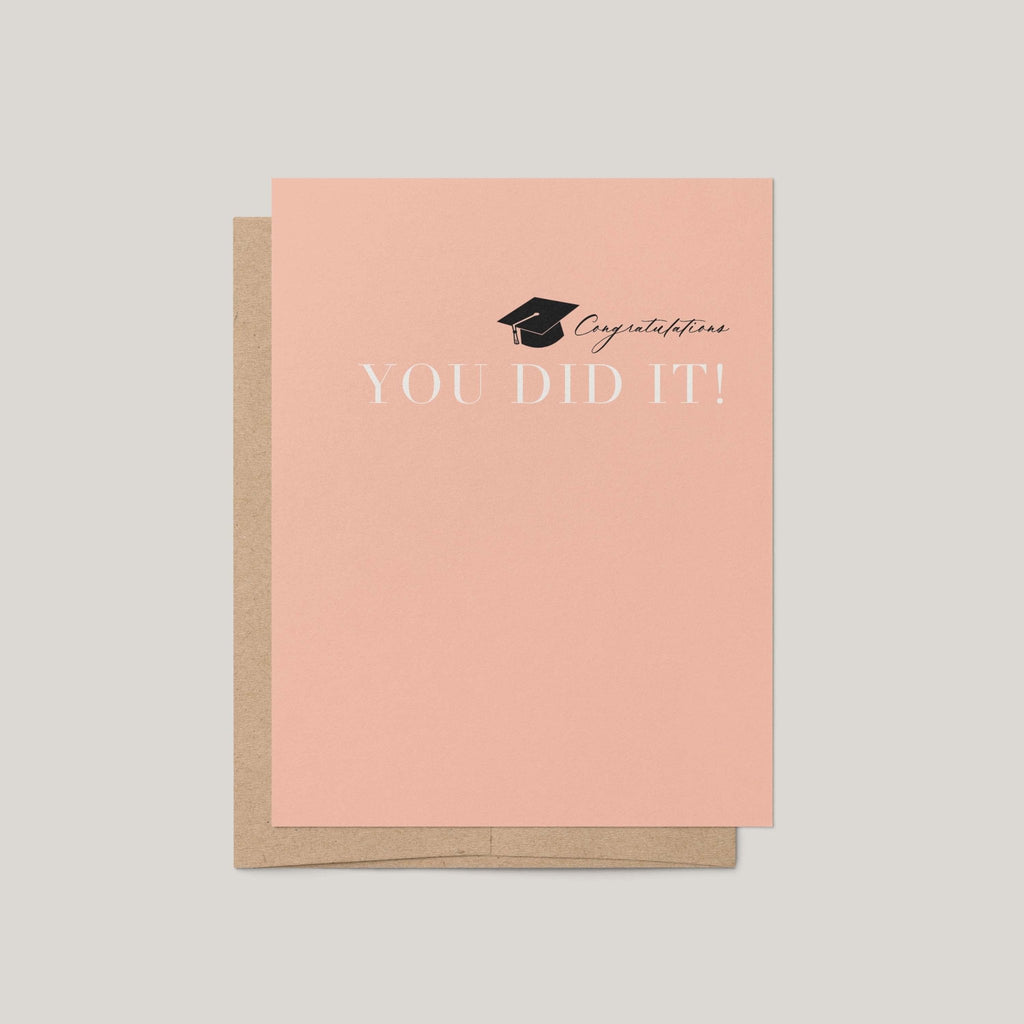 You Did It graduation greeting card by Blú Rose, peach card with graduation cap and congratulations you did it text, shown with kraft envelope