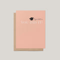 You Did It graduation greeting card by Blú Rose, peach card with graduation cap and congratulations you did it text, shown with kraft envelope