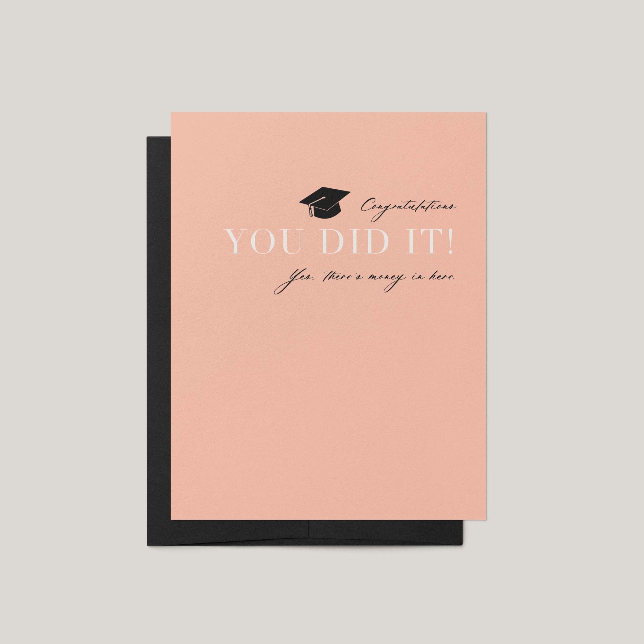 You Did It graduation money greeting card by Blú Rose, peach card with graduation cap and there's money in here text, shown with black envelope