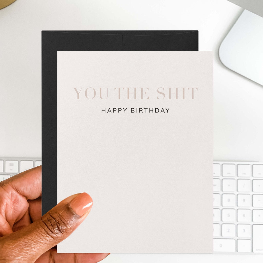 You the Shit funny birthday card by Blú Rose held in hand over a white desk with keyboard and black envelope