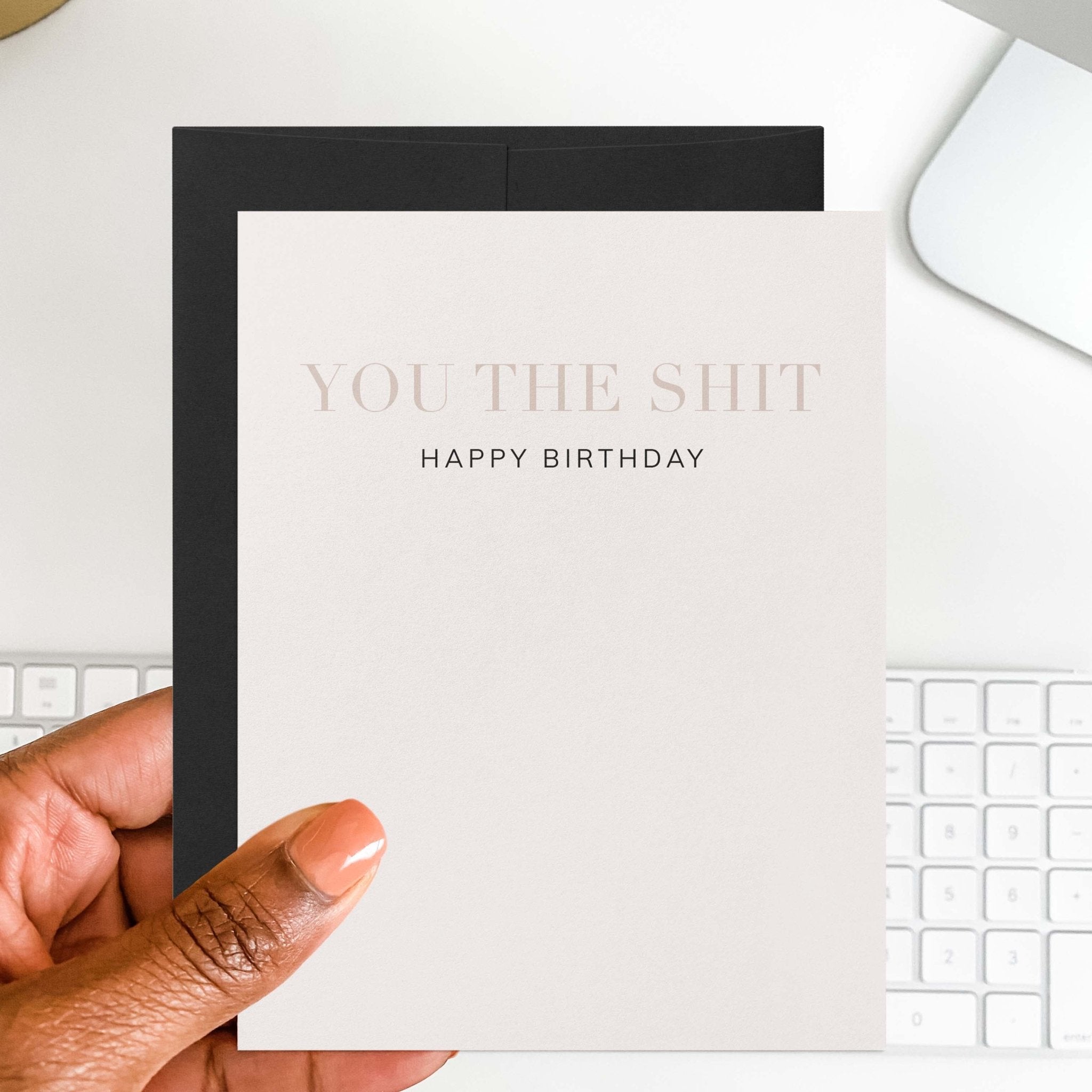 You the Shit funny birthday card by Blú Rose held in hand over a white desk with keyboard and black envelope