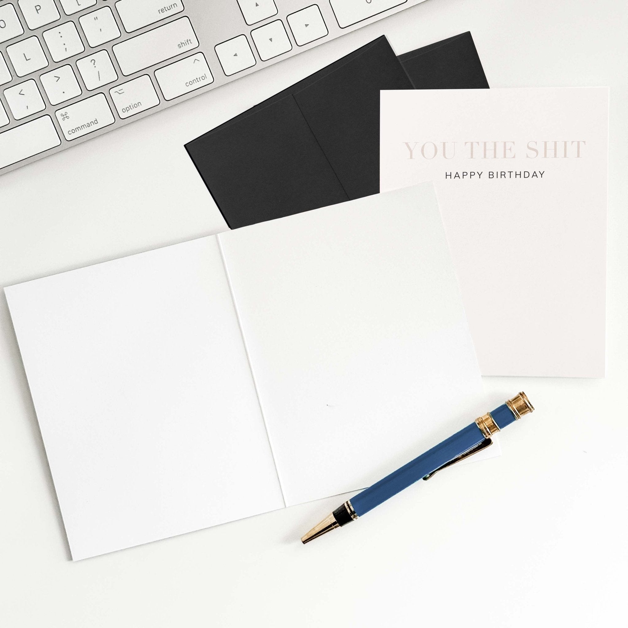 You the Shit birthday card by Blú Rose shown open with blank interior, black envelope and pen on a white desk