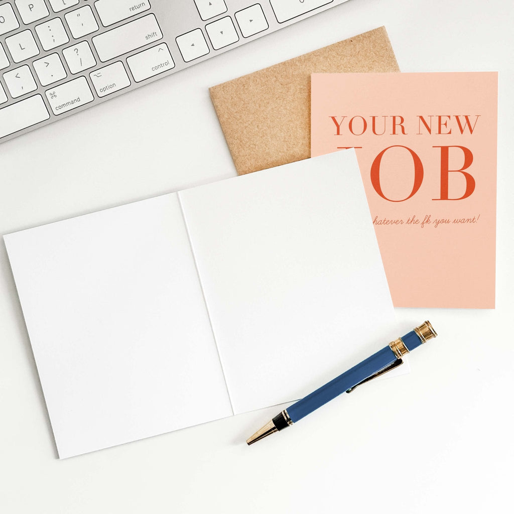 Your New Job Is retirement card by Blú Rose shown open with blank interior, kraft envelope and pen on a white desk