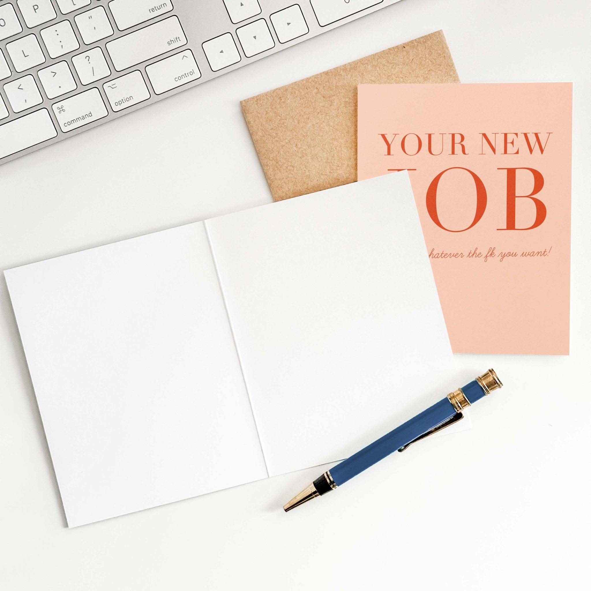 Your New Job Is retirement card by Blú Rose shown open with blank interior, kraft envelope and pen on a white desk