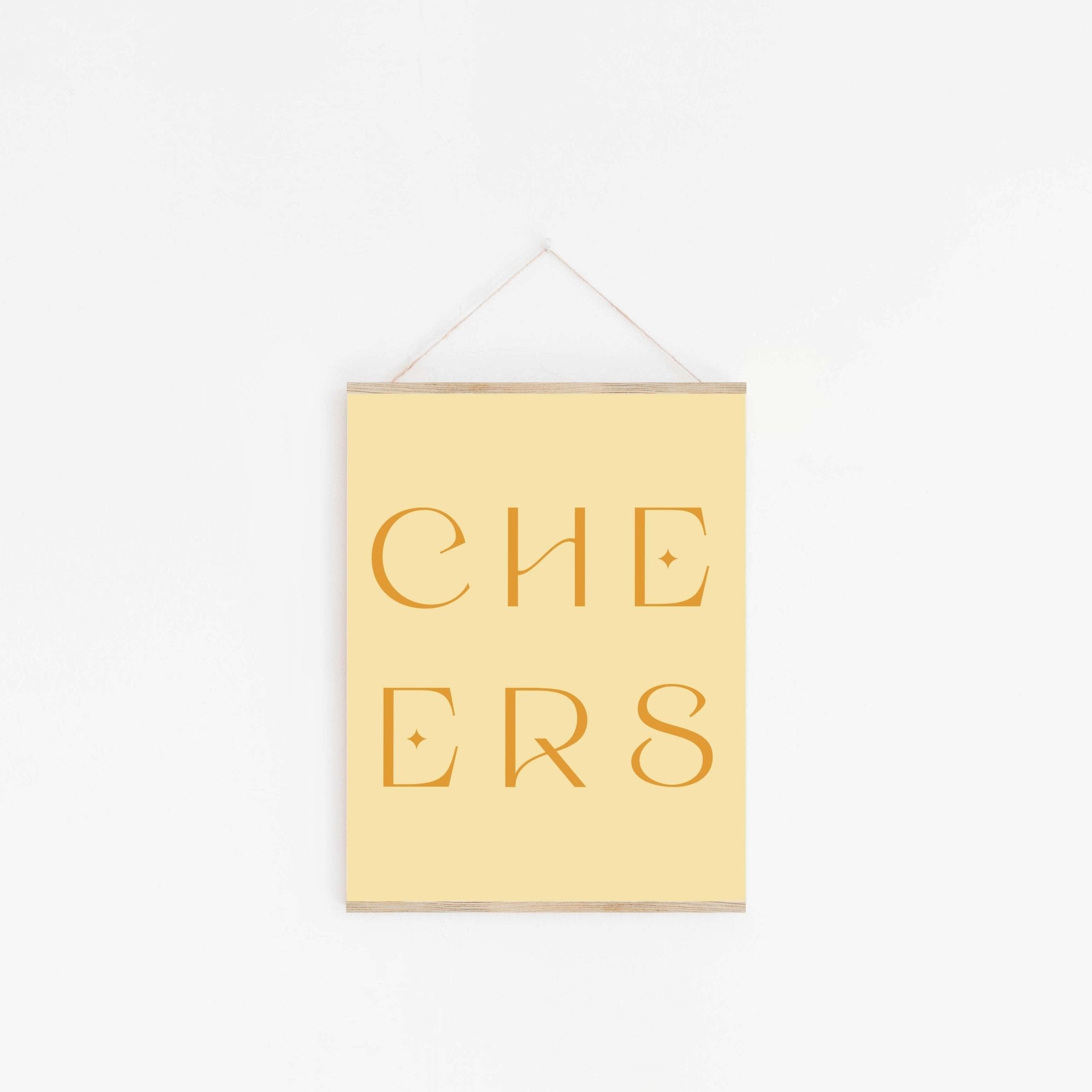 Pastel yellow “CHEERS” typography art print hanging on white wall.