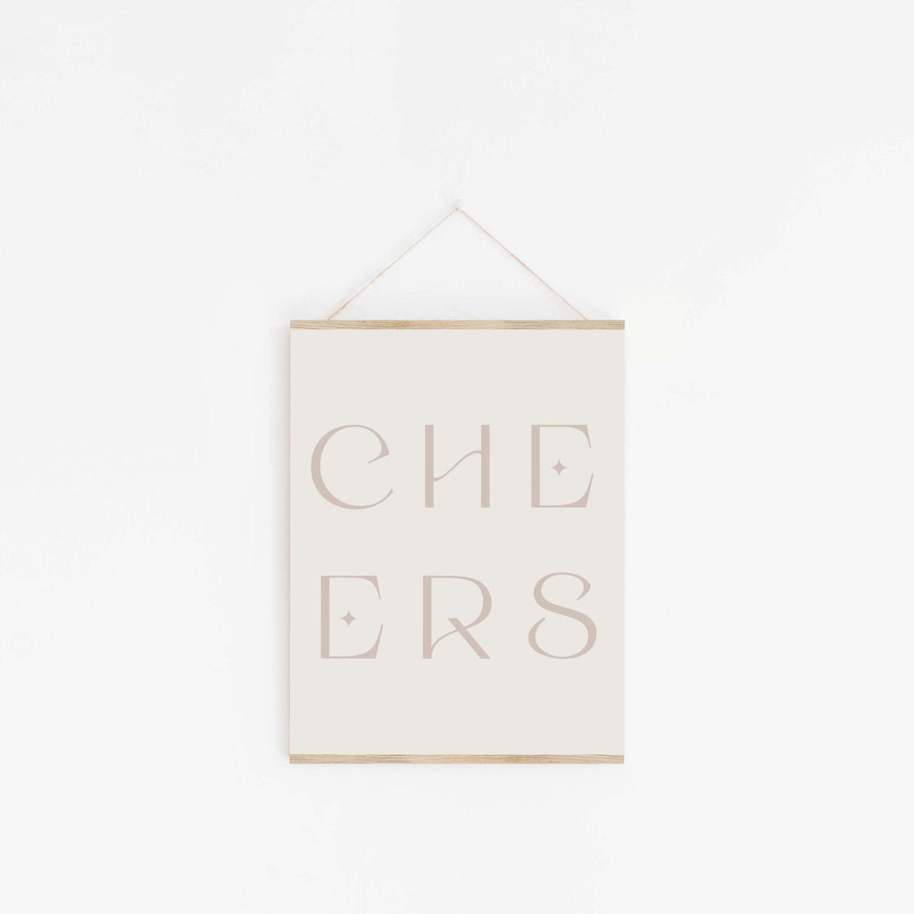 Beige “CHEERS” typography art print hung on a white wall.