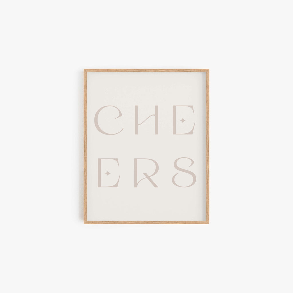 Minimal “CHEERS” typography art print in a neutral beige frame displayed on a white wall.