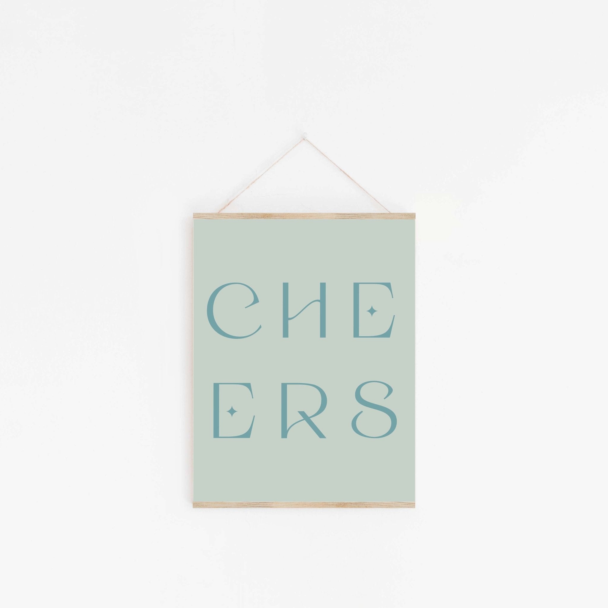 Pastel sage green “CHEERS” typography art print hanging on white wall.