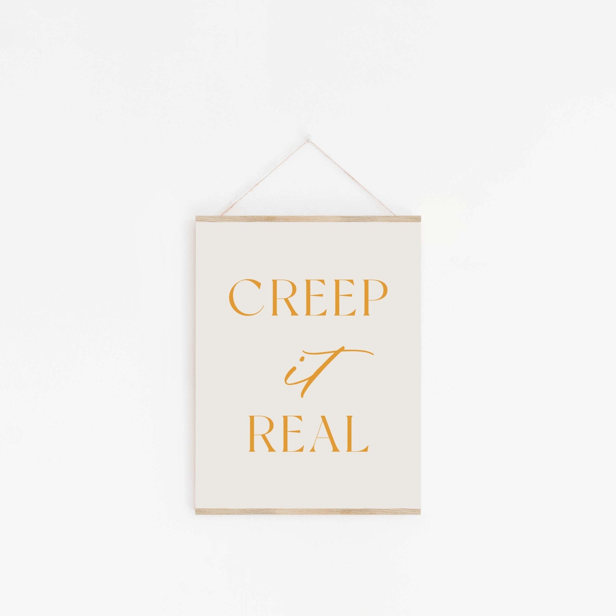 Hanging “Creep it Real” art print displayed on a clean white wall with a simple, minimal setup.