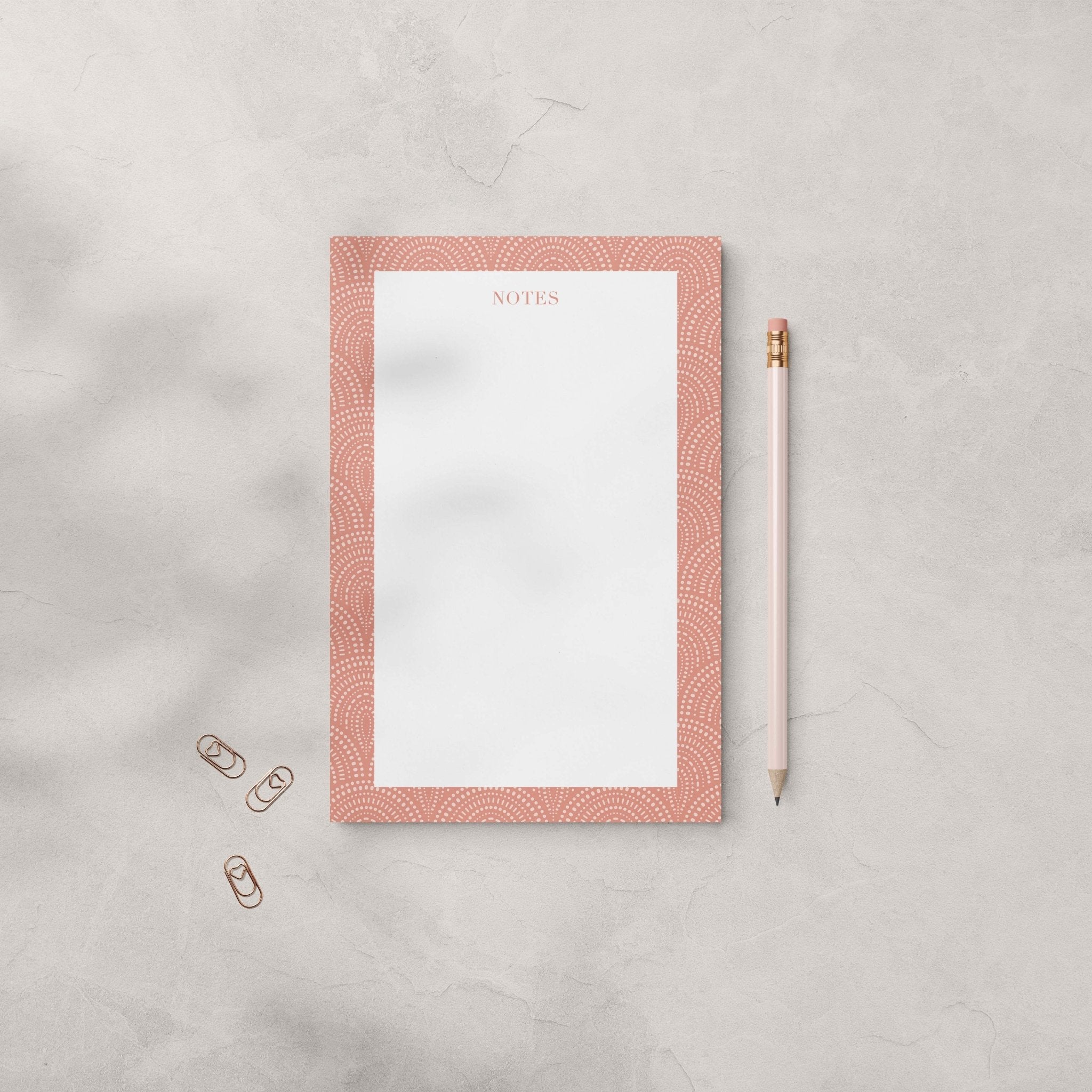 Fancy Arches notepad by Blú Rose, terracotta arch-bordered notepad photographed with a pink pencil and heart paper clips on a gray surface