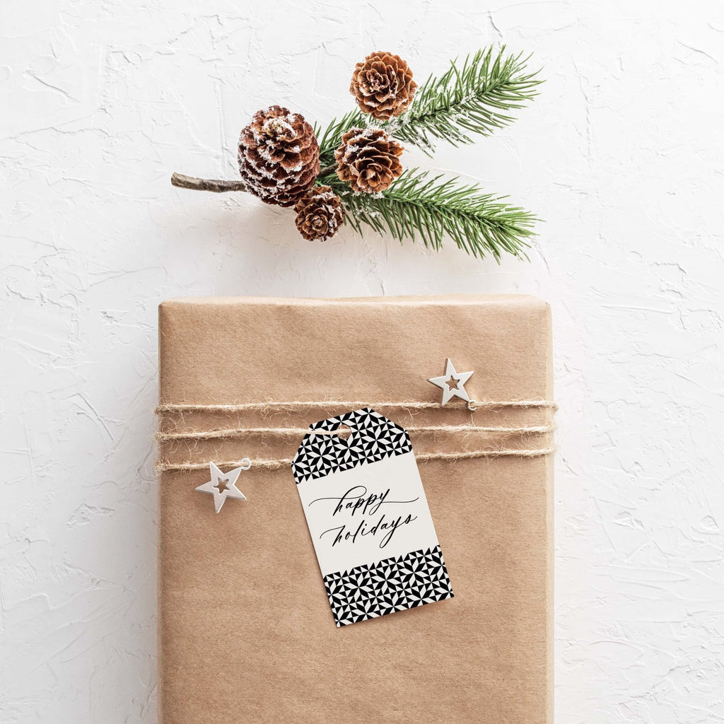 Holiday Pattern gift tags by Blú Rose, 'happy holidays' black and white geometric tag on a kraft-wrapped gift with pinecones and pine
