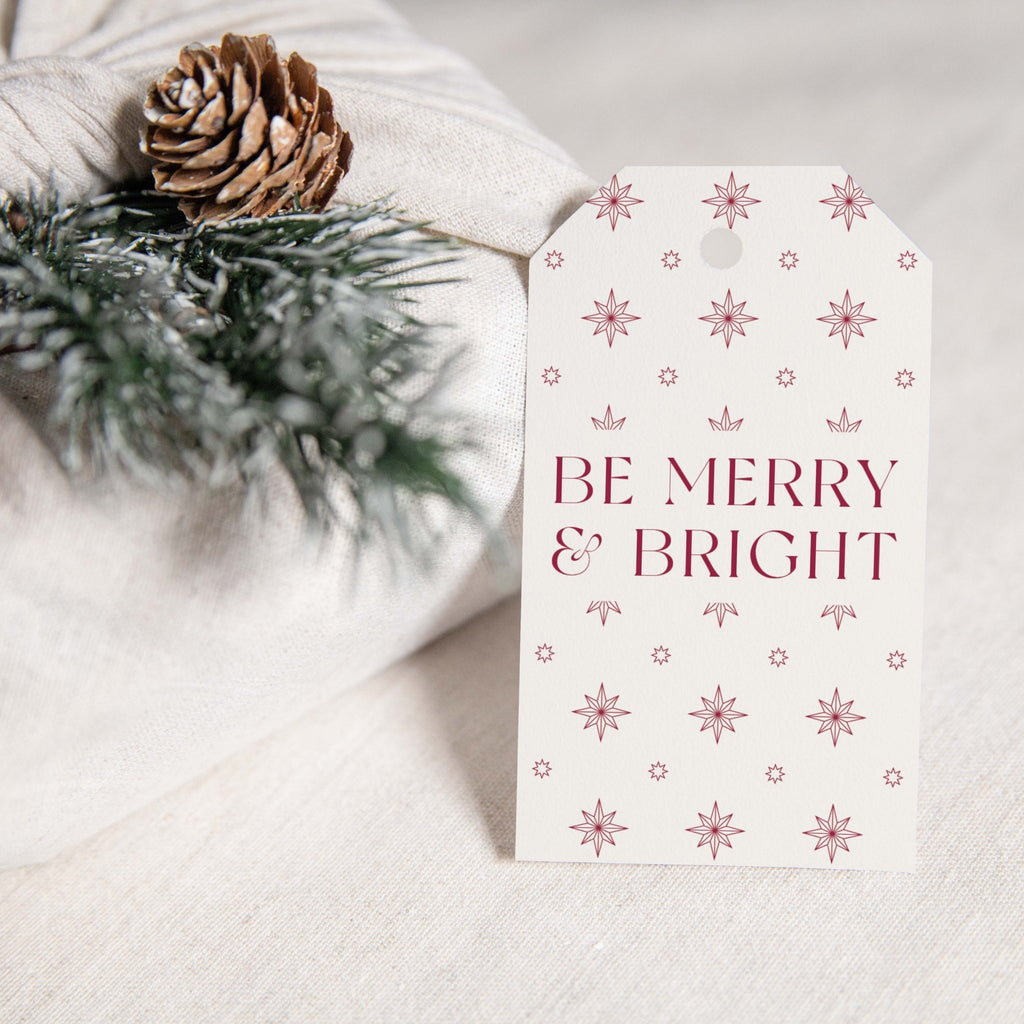 Merry & Bright gift tags by Blú Rose, 'Be Merry & Bright' cream and burgundy star tag styled on white linen with a pinecone and pine sprig