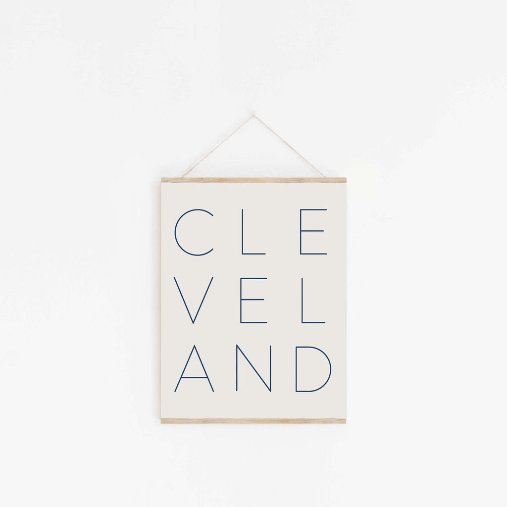 Cleveland typography poster hanging from wooden hanger on off-white background