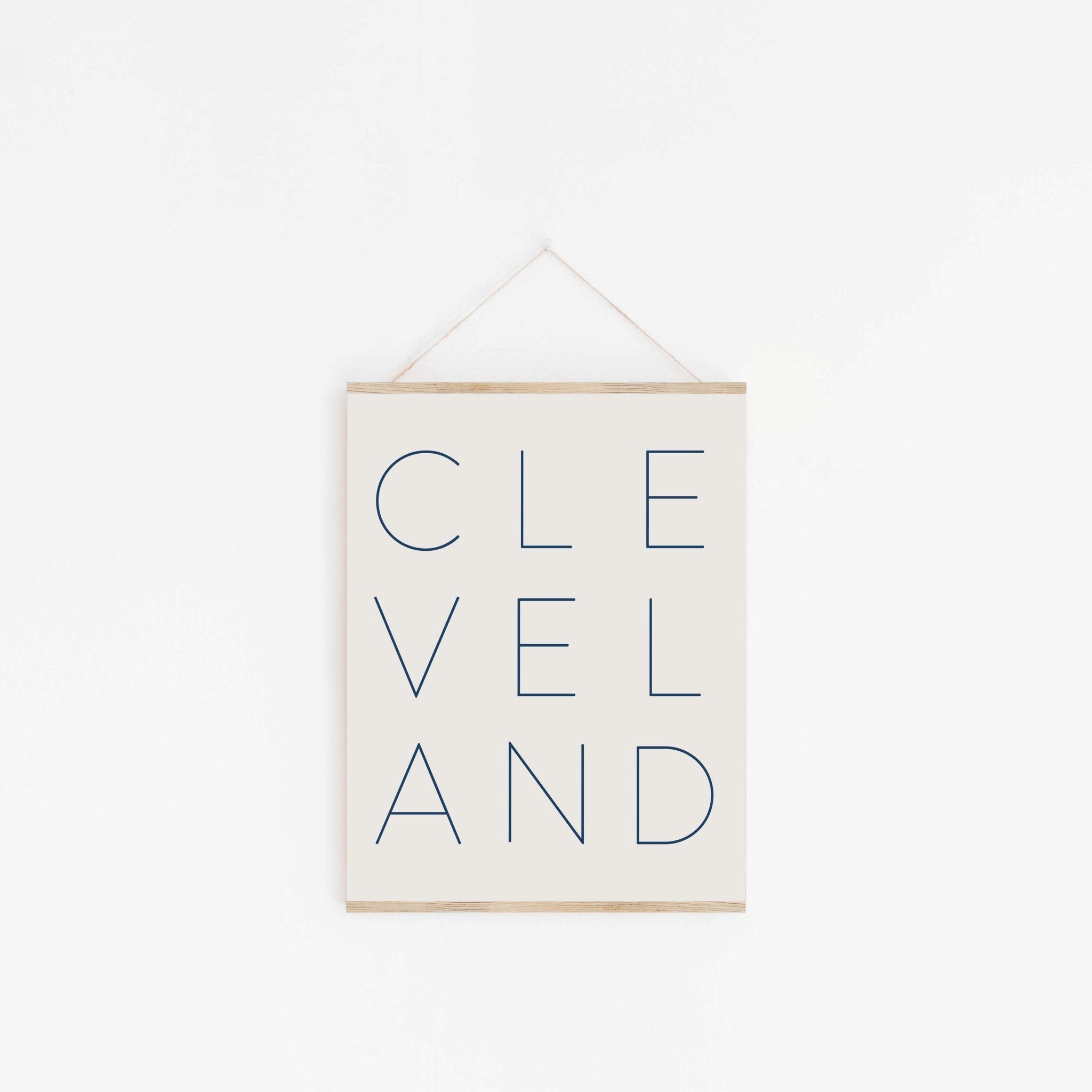 Cleveland typography poster hanging from wooden hanger on off-white background