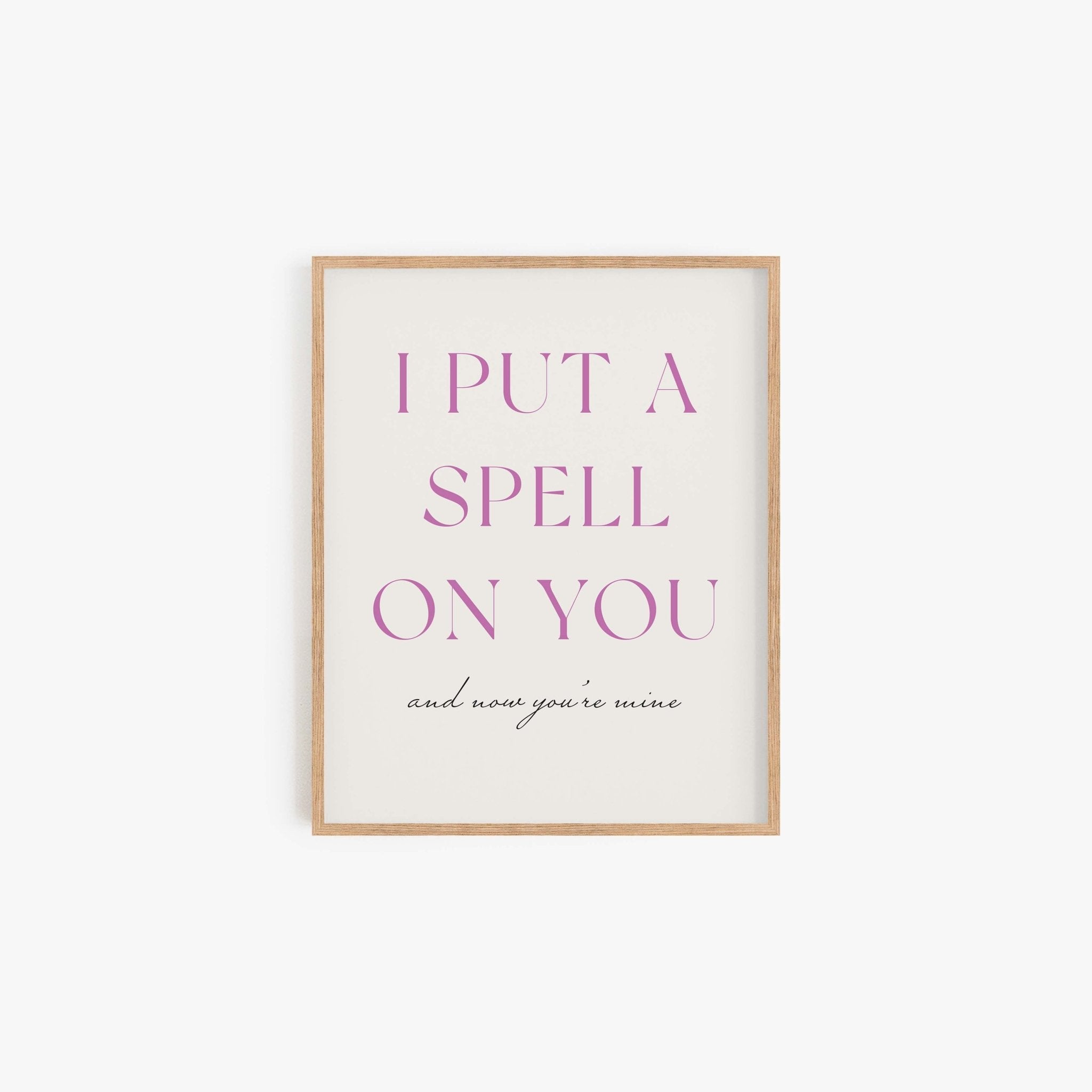Put A Spell On You typography art print in purple lettering on off-white background in light wood frame