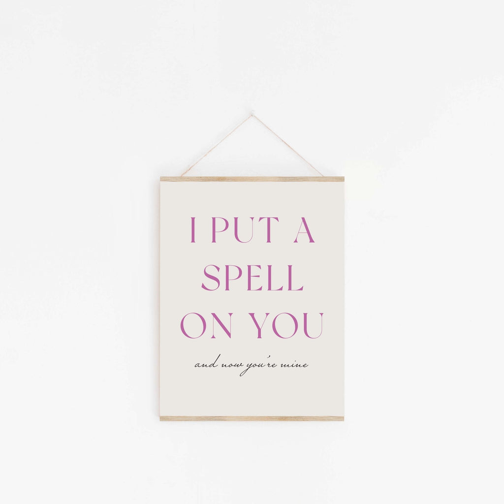 Put A Spell On You purple typography art print hanging from wooden hanger on off-white background