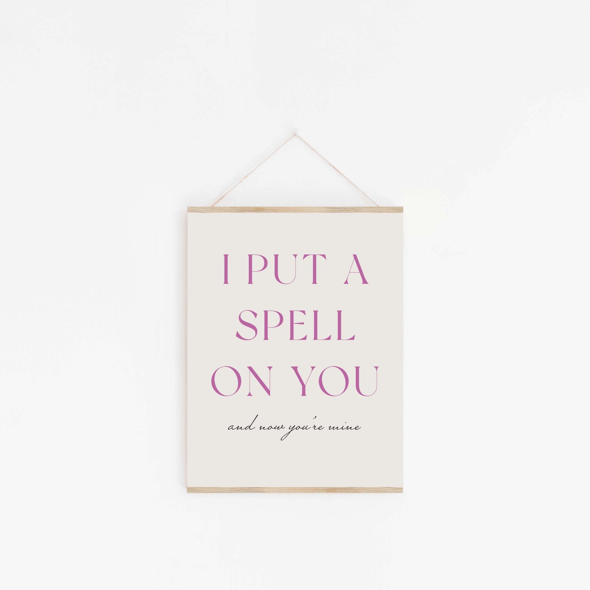 Put A Spell On You purple typography art print hanging from wooden hanger on off-white background