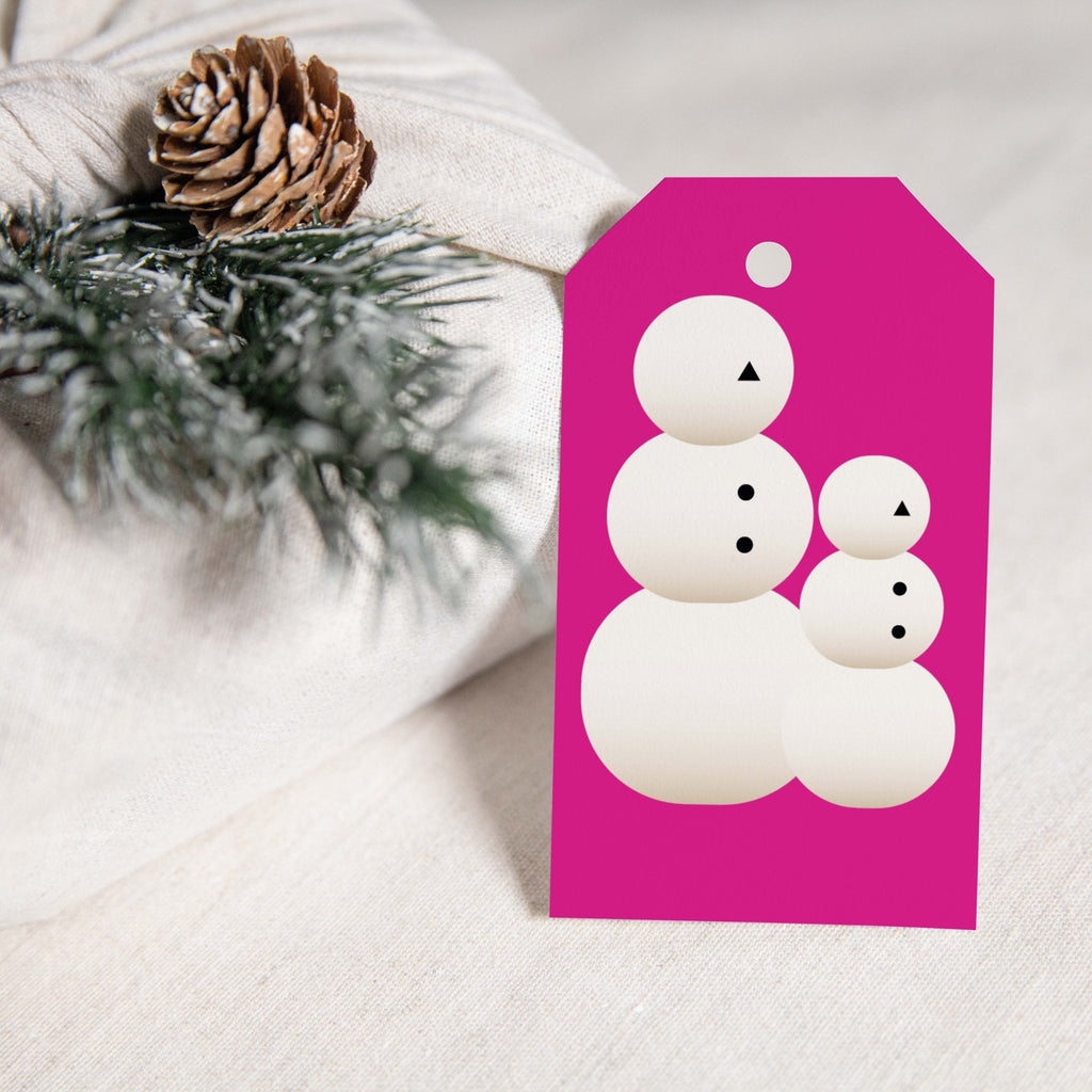 Snow People gift tags by Blú Rose, magenta snow people family tag styled on white linen with a pinecone and pine sprig