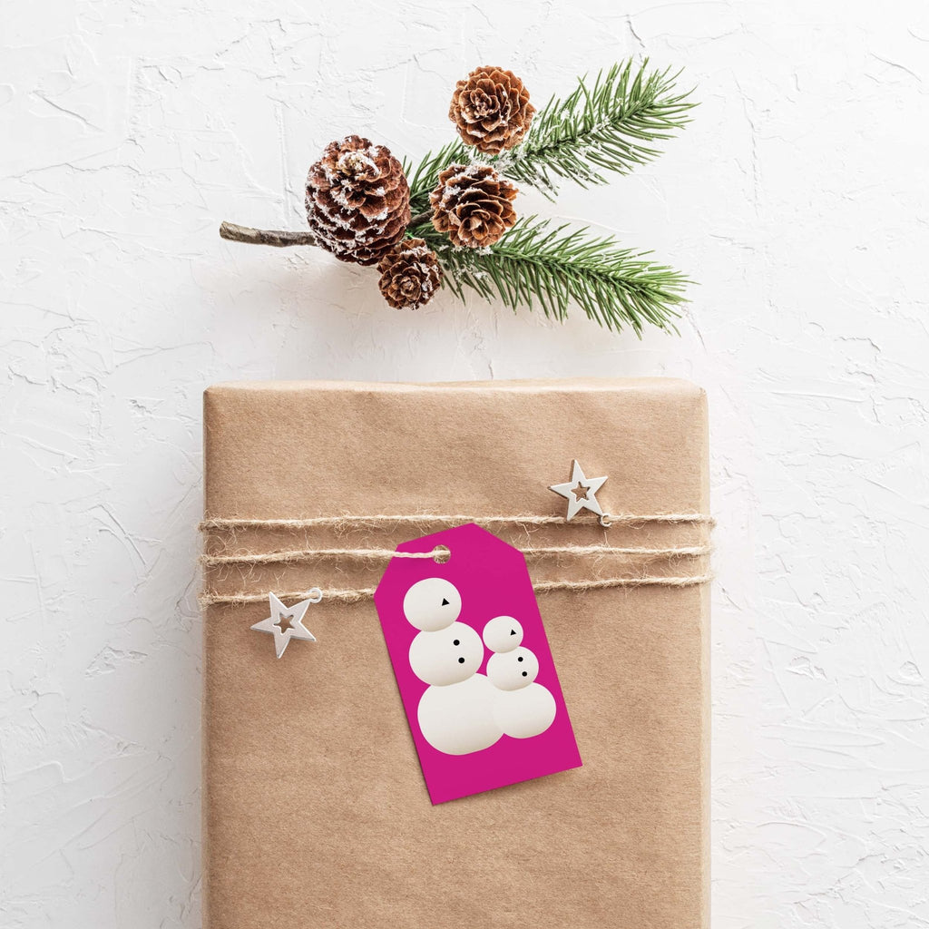 Snow People gift tags by Blú Rose, magenta snow people tag on a kraft-wrapped gift with pinecones and pine